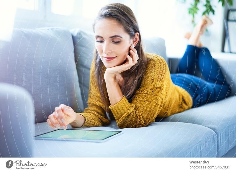 Young oman lying on sofa and using tablet human human being human beings humans person persons caucasian appearance caucasian ethnicity european 1