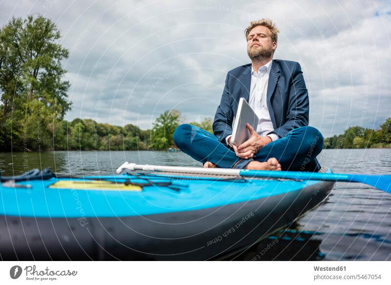 Businessman with laptop sitting on SUP board on a lake business life business world business person businesspeople Business man Business men Businessmen