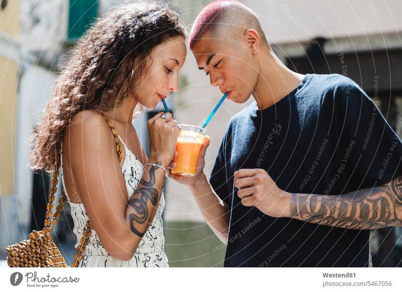 Young couple drinking fruit juice together touristic tourists back-pack back-packs backpacks rucksack rucksacks drinking straw drinking straws Emotions Feeling