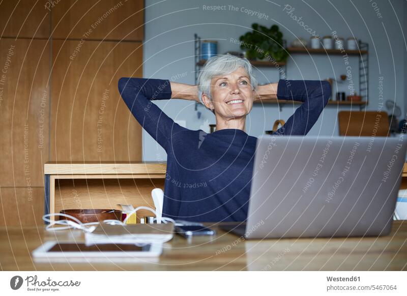Smiling senior woman with hands behind head relaxing while sitting at home color image colour image indoors indoor shot indoor shots interior interior view