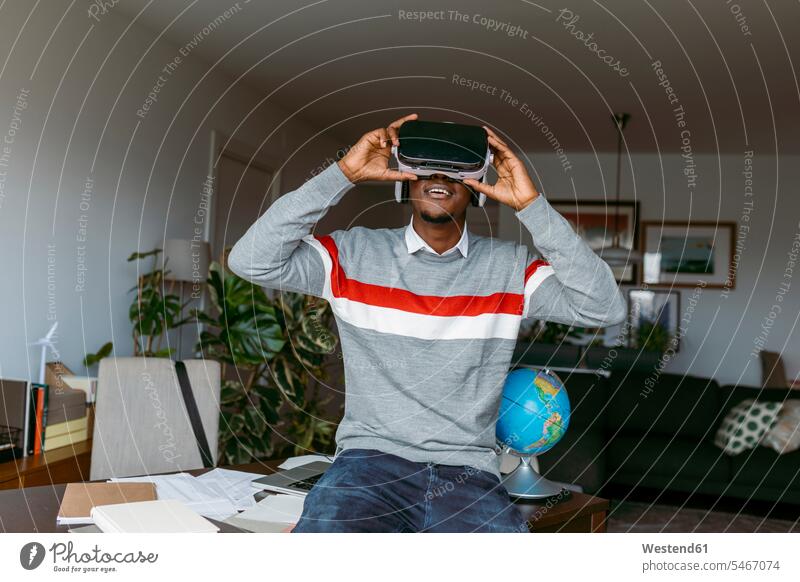 Businessman using virtual reality headset while sitting on desk at home color image colour image indoors indoor shot indoor shots interior interior view