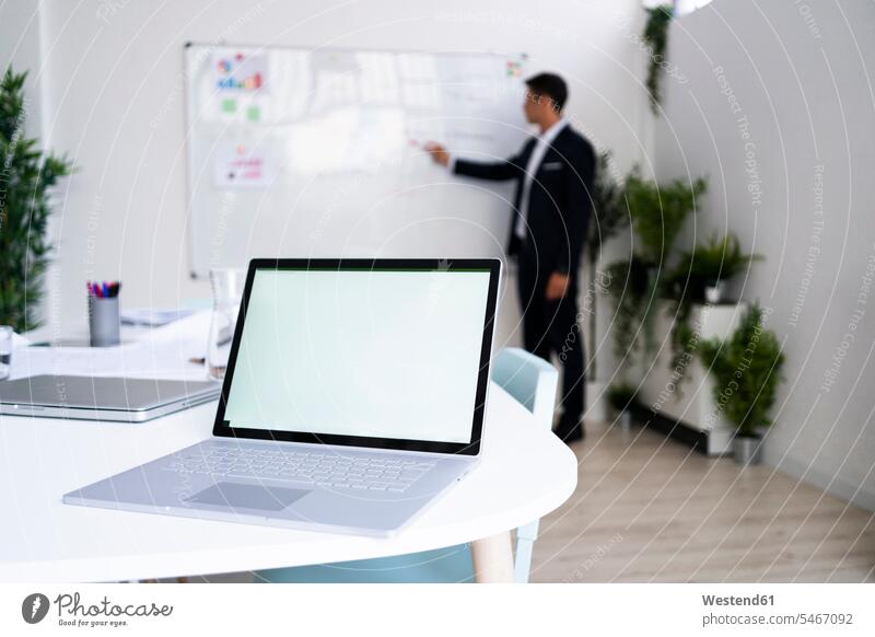 Laptop with blank screen on desk while businessman planning strategy at workplace color image colour image indoors indoor shot indoor shots interior