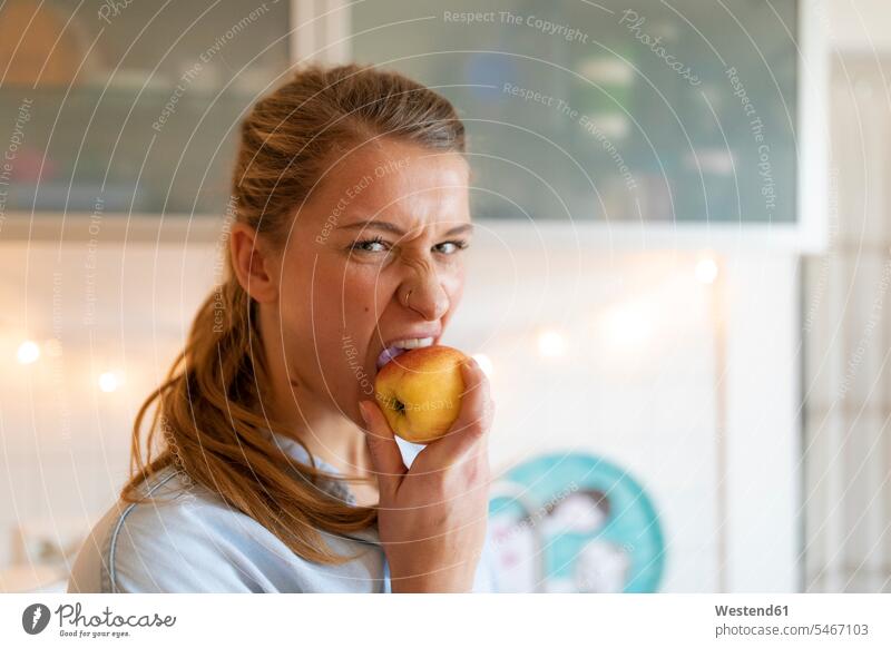 Portrait of young woman eating an apple at home human human being human beings humans person persons celibate celibates singles solitary people solitary person