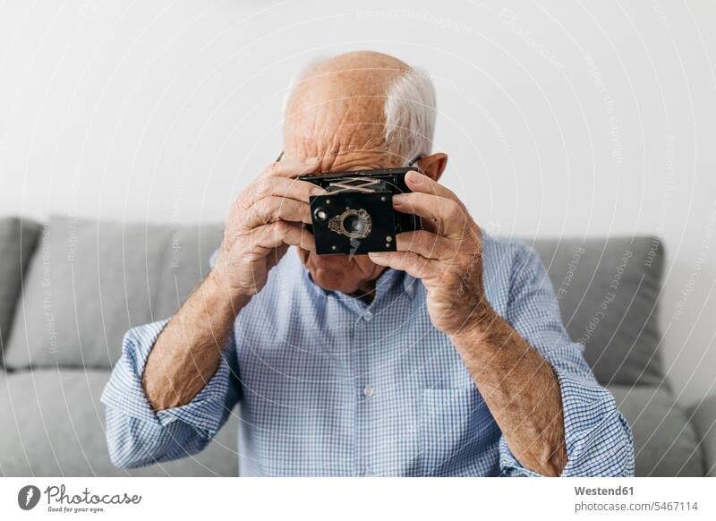 Senior man taking a photo with an old photo camera cameras photographing leisure free time leisure time hobby hobbies leisure activity leisure activities