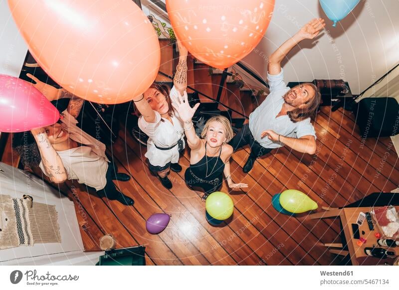 Cheerful friends dancing with colorful balloons during party at home color image colour image indoors indoor shot indoor shots interior interior view Interiors