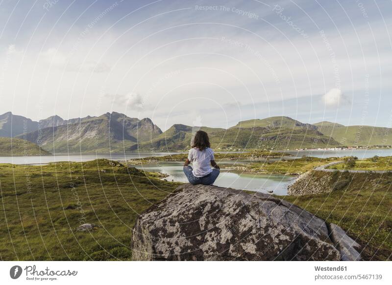 Young woman sitting on a rock, looking at view, meditating, Lapland, Norway rocks young women young woman meditation meditations thinking Seated females Adults