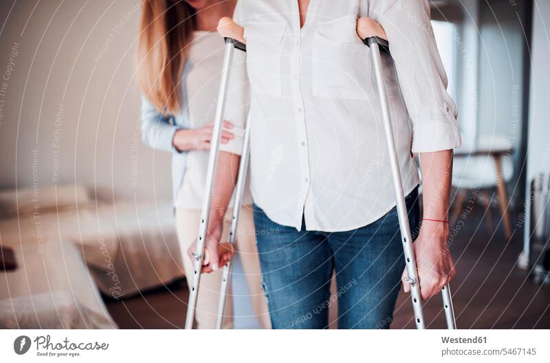 Daughter helping her mother to walk with crutches go going at home health healthcare Healthcare And Medicines medical medicine disease diseases ill illnesses