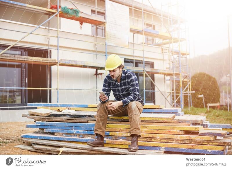 Worker on a construction site having a break checking cell phone human human being human beings humans person persons caucasian appearance caucasian ethnicity