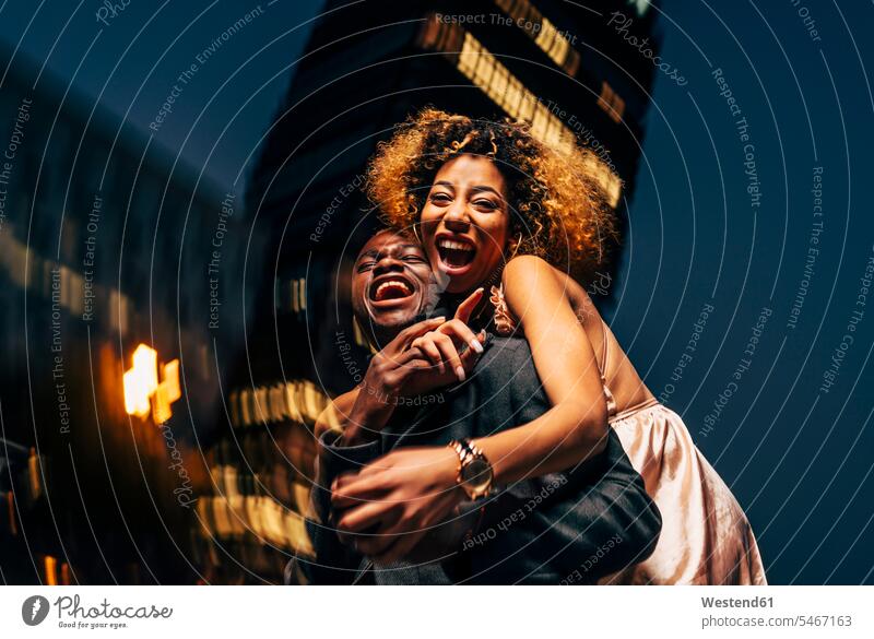 Laughing young couple having fun at night in the city Fun funny town cities towns laughing Laughter twosomes partnership couples by night nite night photography