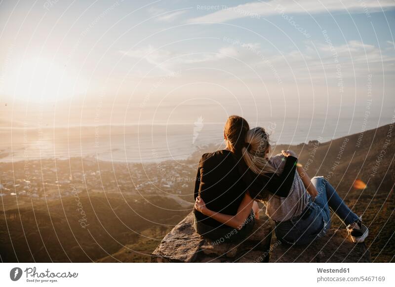 South Africa, Cape Town, Kloof Nek, two women sitting on rock at sunset girlfriend Girlfriends girl friend girl friends Seated sunsets sundown rocks woman