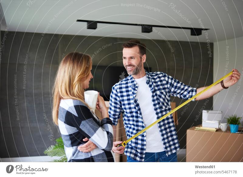 Couple moving into new flat measuring with tape measure move in couple twosomes partnership couples flats apartment apartments measuring tapes tape measures