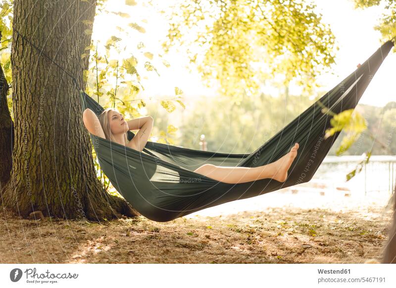 Young woman relaxing in hammock by the lake hammocks summer time summertime summery happy lyrical Romance free time leisure time Harmonious Lifestyle holiday