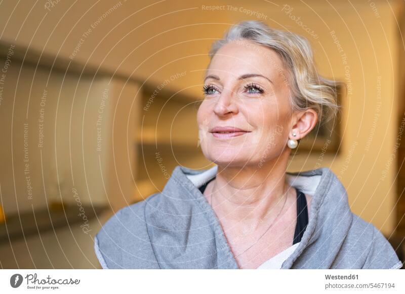 Portrait of happy mature woman in the living room smiling smile Earring Earrings looking up mascara Best Ager best age Best Agers looking at distance