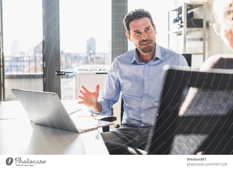 Businessman using laptop while discussing with colleague at office color image colour image indoors indoor shot indoor shots interior interior view Interiors