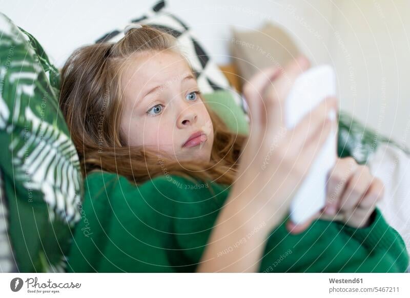 Portrait of girl wearing green pullover lying on bed starring at cell phone human human being human beings humans person persons caucasian appearance
