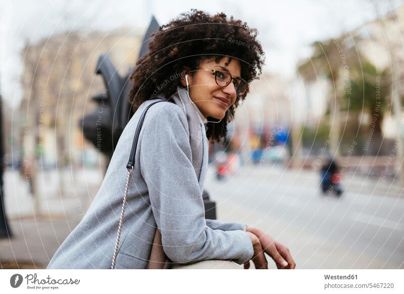 Spain, Barcelona, smiling woman with earphones in the city looking away look away smile town cities towns females women ear phone ear phones view seeing viewing