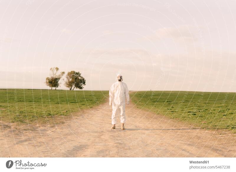 Man wearing protective suit and mask standing on dirt track in the countryside Occupation Work job jobs profession professional occupation masks sciences