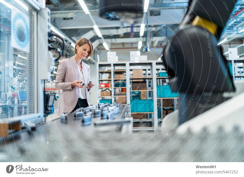 Businesswoman examining workpieces in a modern factory hall human human being human beings humans person persons caucasian appearance caucasian ethnicity