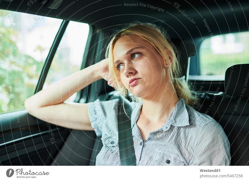 Serious blond young woman in a car females women automobile Auto cars motorcars Automobiles serious earnest Seriousness austere blond hair blonde hair Adults