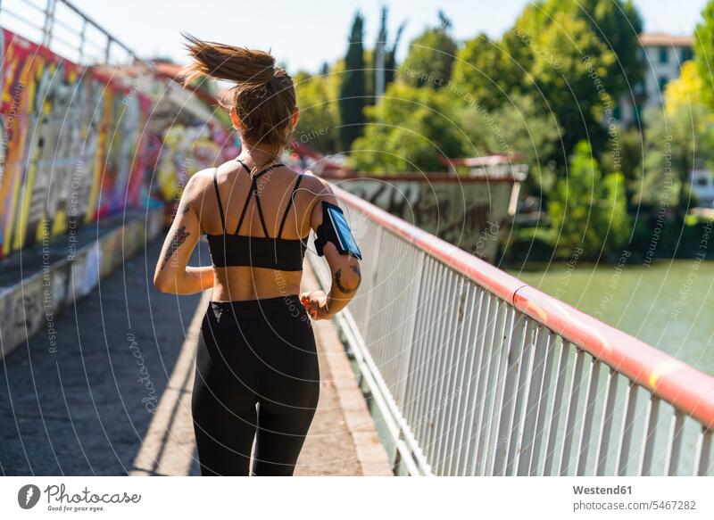 Rear view of young woman running on a bridge telecommunication phones telephone telephones cell phone cell phones Cellphone mobile mobile phones mobiles