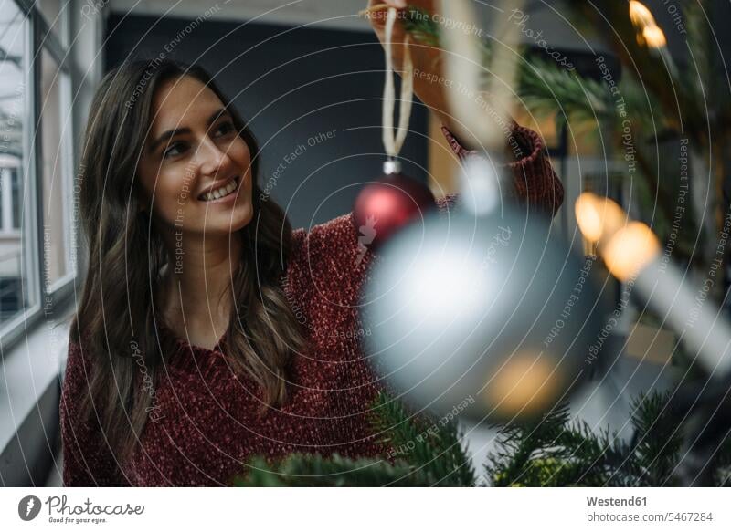 Smiling young woman decorating Christmas tree caucasian caucasian ethnicity caucasian appearance european Joy enjoyment pleasure Pleasant delight smiling smile