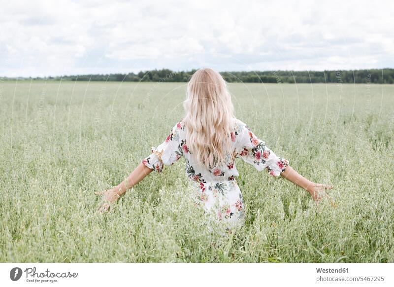 Young woman with blond hair standing amidst oats field against cloudy sky color image colour image leisure activity leisure activities free time leisure time