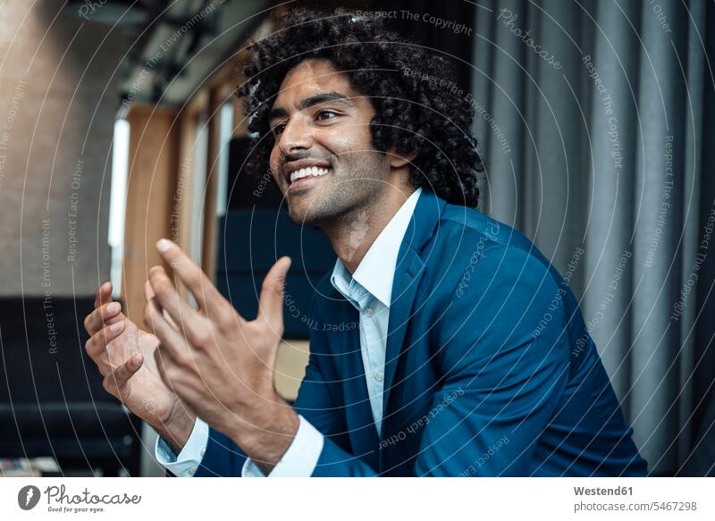 Smiling handsome businessman gesturing while sitting in office color image colour image Germany indoors indoor shot indoor shots interior interior view
