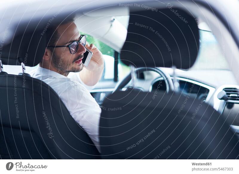 Businessman sitting in car talking on the phone Business man Businessmen Business men Seated automobile Auto cars motorcars Automobiles speaking call