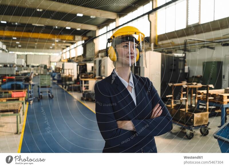Portrait of a confident businesswoman wearing safety helmet and earmuffs in a factory human human being human beings humans person persons caucasian appearance