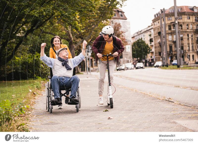 Senior man in wheelchair having fun with his adult grandchildren outdoors human human being human beings humans person persons caucasian appearance
