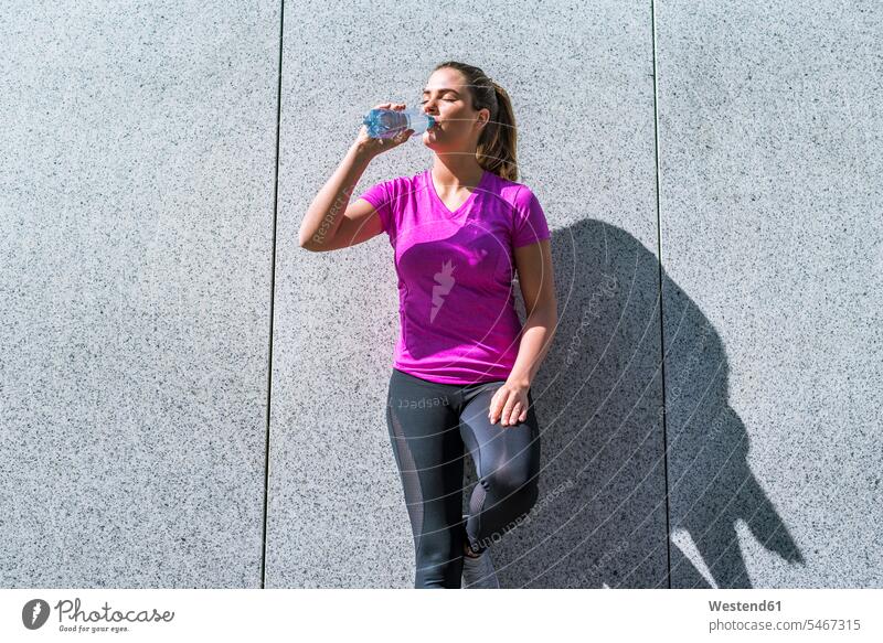 Young woman having a break from exercising drinking from bottle Bottle Bottles females women exercise training practising Adults grown-ups grownups adult people
