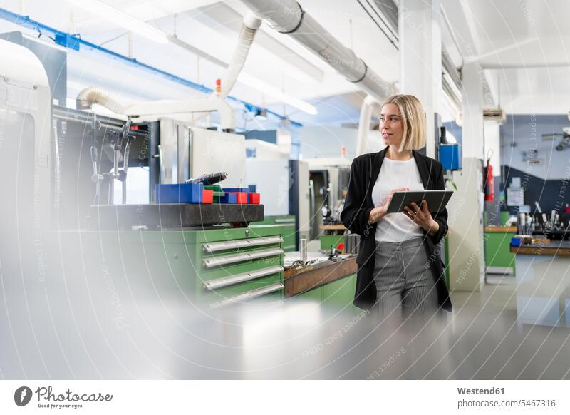 Woman holding tablet in factory hall looking around Occupation Work job jobs profession professional occupation business life business world business person