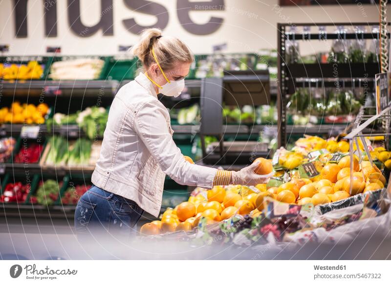 Teenage girl wearing protectice mask and gloves choosing fruits at supermarket human human being human beings humans person persons caucasian appearance