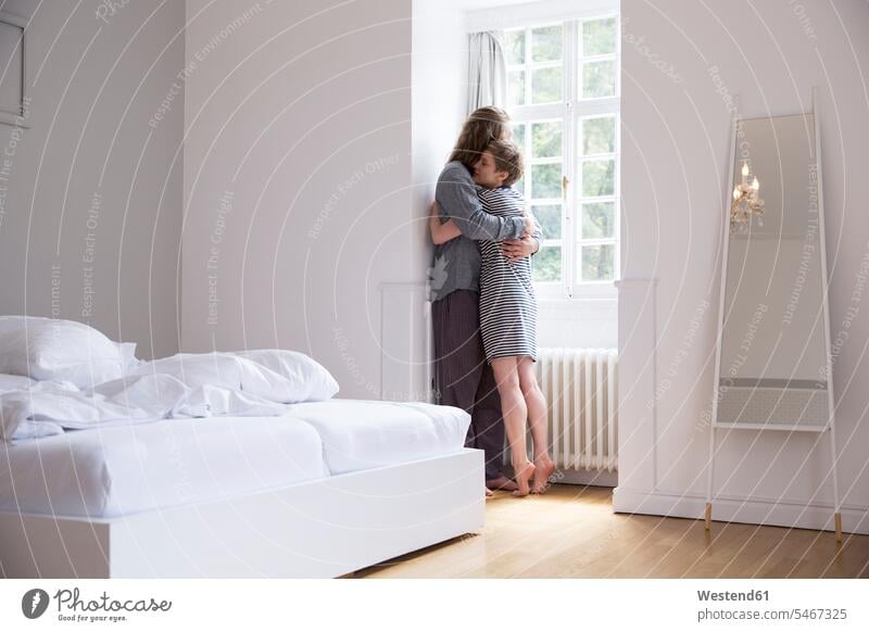 Young couple hugging at the window in bedroom at home windows Bed - Furniture beds embrace Embracement delight enjoyment Pleasant pleasure Secure happy Emotions