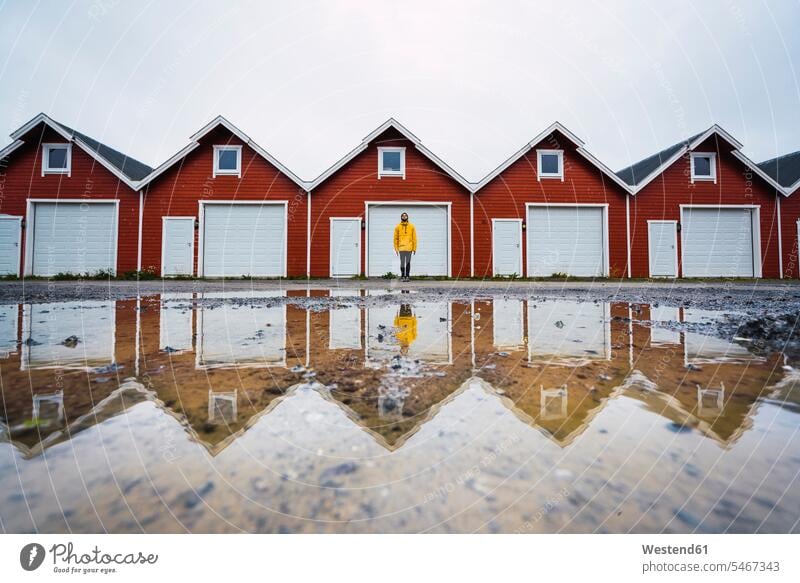 Norway, man standing in front of row of huts men males in a row Rows Adults grown-ups grownups adult people persons human being humans human beings building