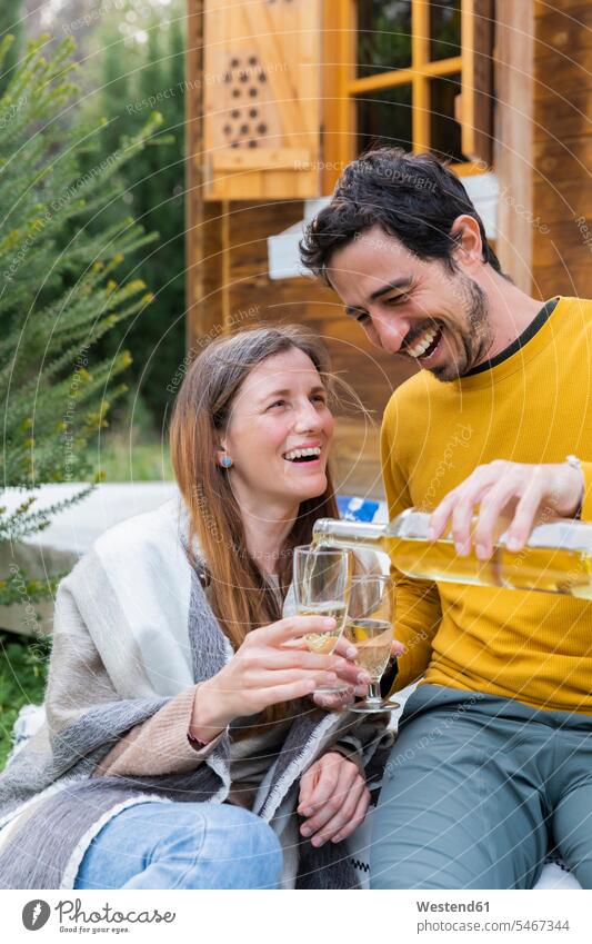 Happy man pouring wine in glass held by girlfriend while sitting outdoors color image colour image Spain leisure activity leisure activities free time