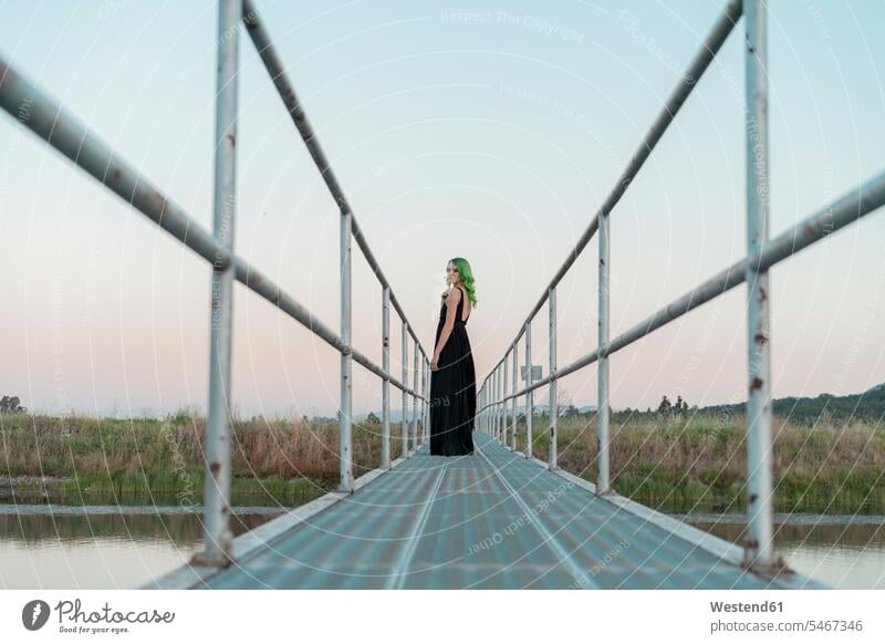 Young woman with dyed green hair standing on a footbridge looking back females women foot bridges coloured people persons human being humans human beings Adults