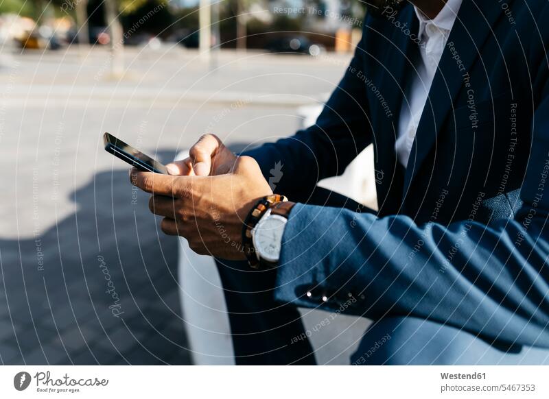 Close-upof businessman sitting outdoors using cell phone Businessman Business man Businessmen Business men males sunshine Sunny Day sunny Seated mobile phone