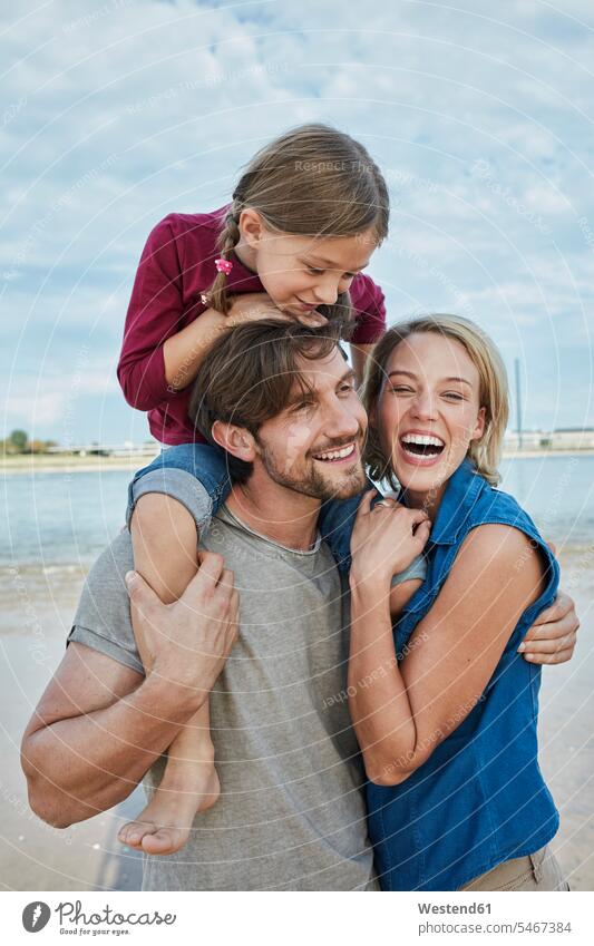 Germany, Duesseldorf, happy family with daughter at Rhine riverbank happiness families Affection Affectionate daughters River Rivers riverside people persons