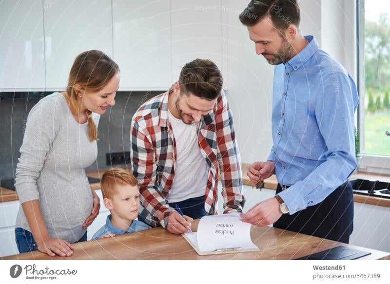 Family with real estate agent signing contract in kitchen of new apartment contracts family families realtor signature flat flats apartments document paper