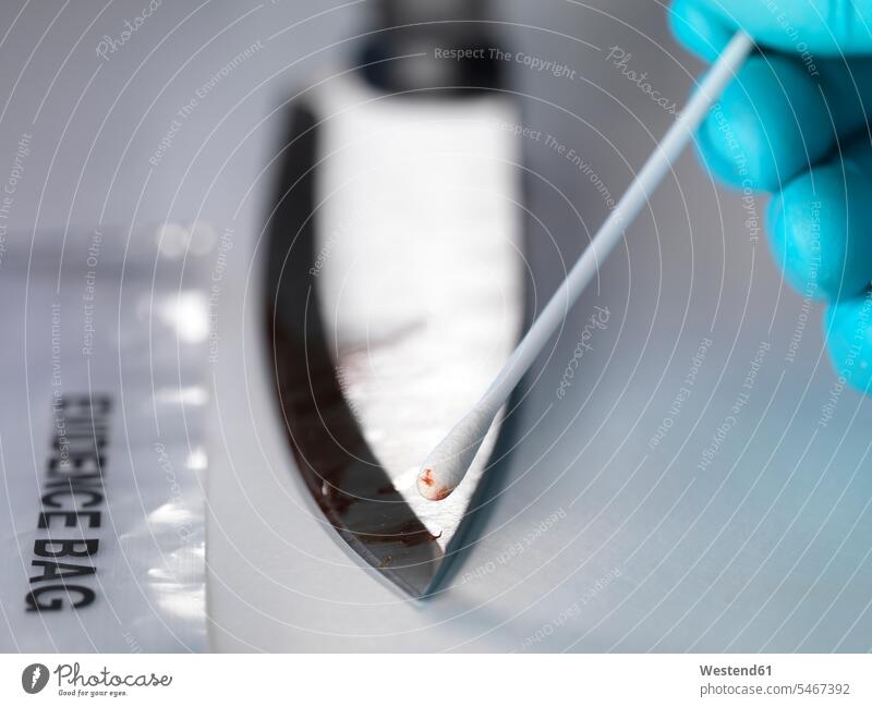 Forensic scientist taking DNA evidence from a blood smeared knife (value=0) human human being human beings humans person persons caucasian appearance