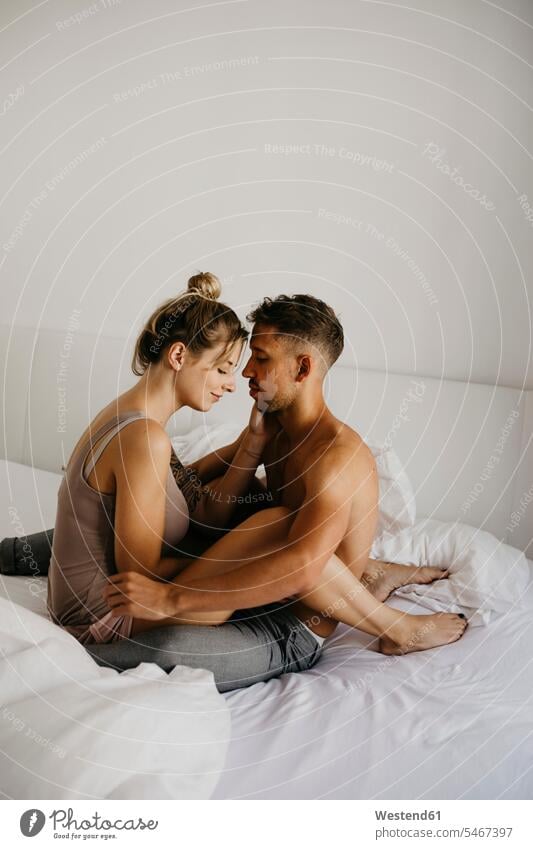Romantic young couple sitting on bed romantic lyrical Romance beds Seated twosomes partnership couples people persons human being humans human beings nightshirt