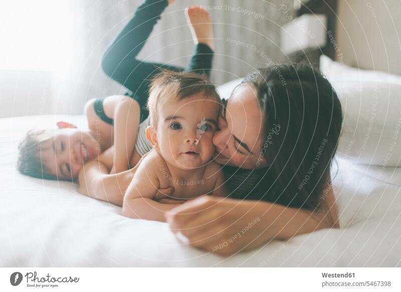 Mother and two boys cuddling in bed at home beds cuddle snuggle snuggling smile delight enjoyment Pleasant pleasure Secure indulgence indulging savoring happy