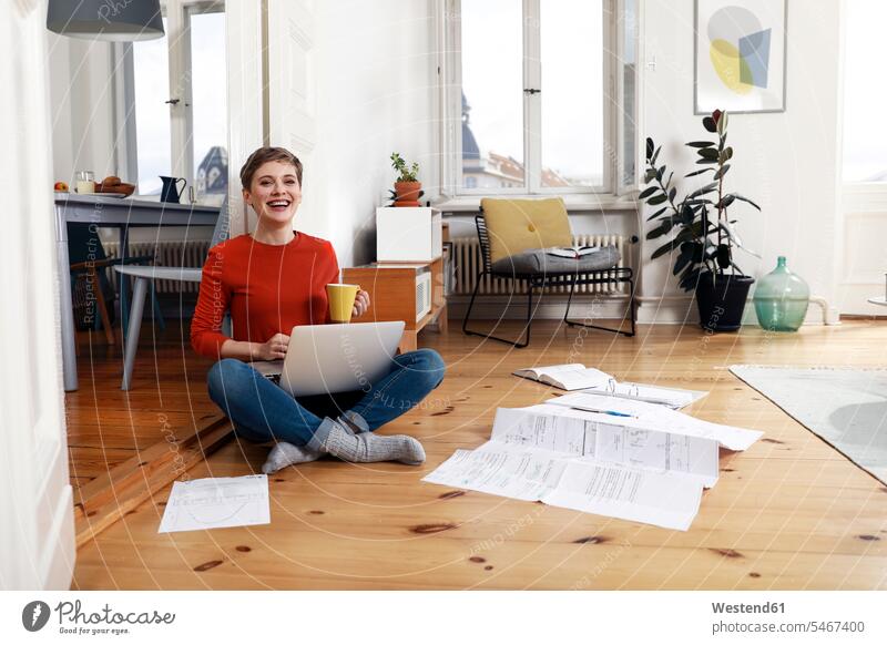 Woman sitting cross-legged on floor of her home, using laptop tailor seat document paper documents papers folder folders Seated working At Work woman females