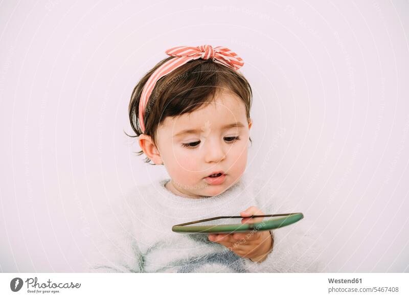 Portrait of baby girl looking at cell phone Smartphone iPhone Smartphones portrait portraits eyeing baby girls female mobile phone mobiles mobile phones