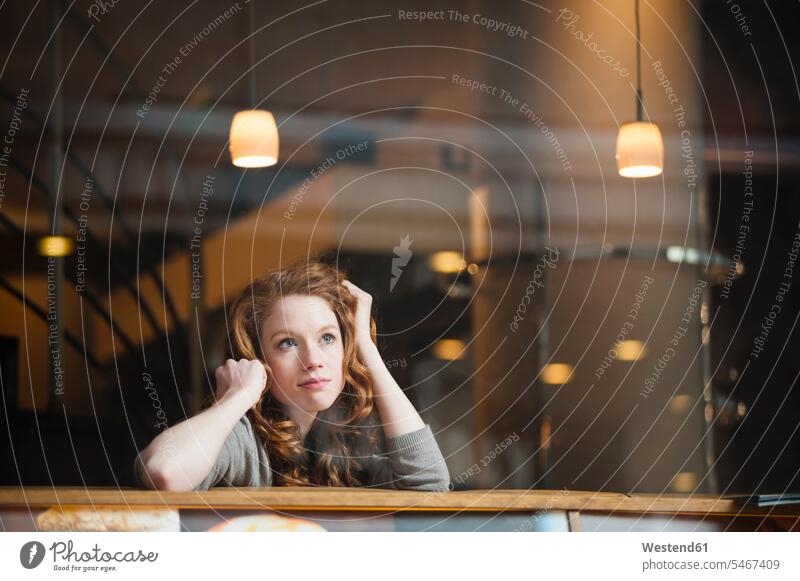 Thoughtful woman leaning on table seen through window in coffee shop color image colour image outdoors location shots outdoor shot outdoor shots day