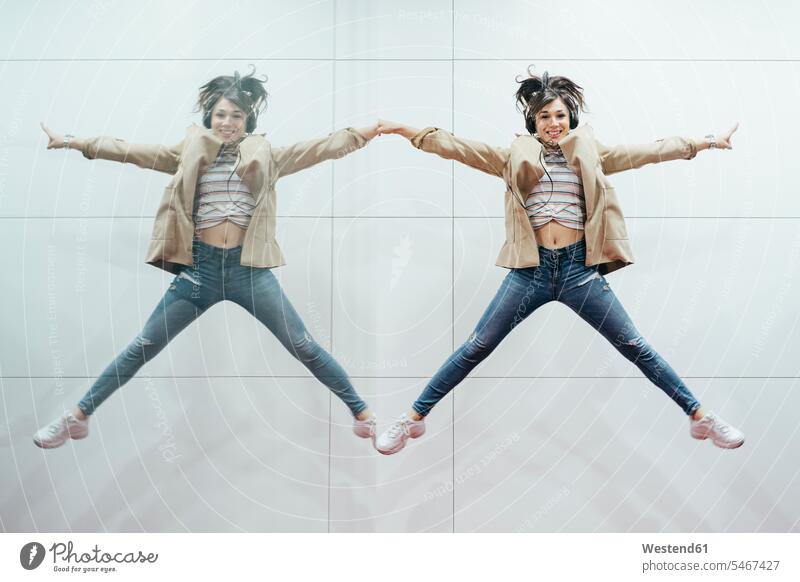 Happy woman with headphones jumping in the air reflected in mirror mirrors headset hear smile Ardor Ardour enthusiasm enthusiastic excited delight enjoyment