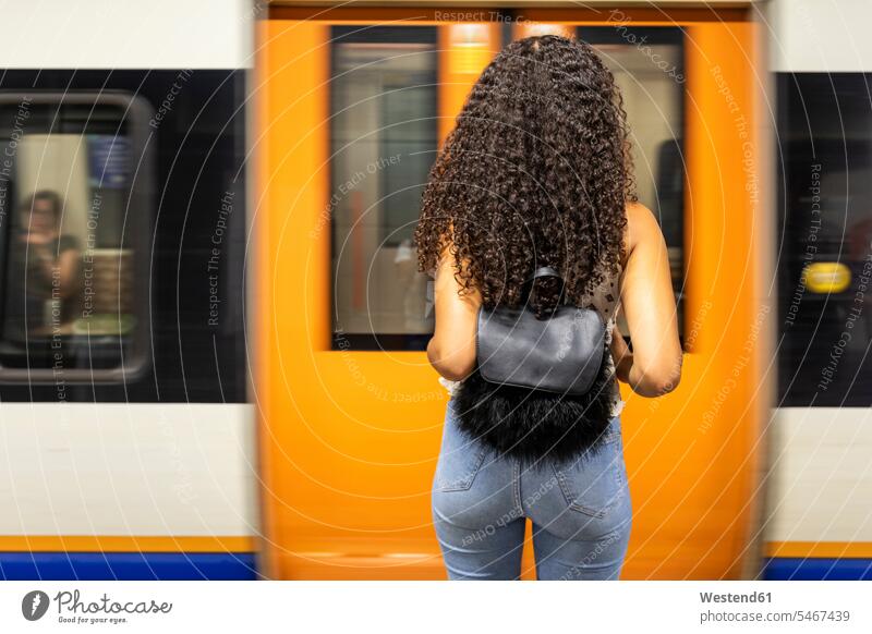 UK, London, rear view of young woman waiting at underground station platform underground train females women Subway Platform railway railroad transportation