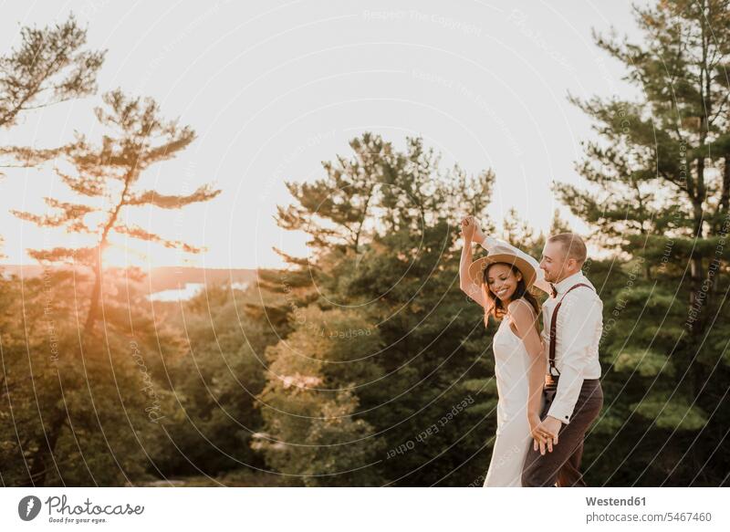 Bride and bridegroom dancing in forest during sunset color image colour image outdoors location shots outdoor shot outdoor shots sunsets sundown atmosphere