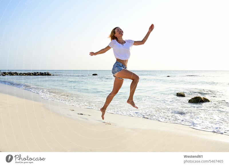 Beautiful woman running and jumping for joy on the beach delight enjoyment Pleasant pleasure Cheerfulness exhilaration gaiety gay glad Joyous merry happy Power